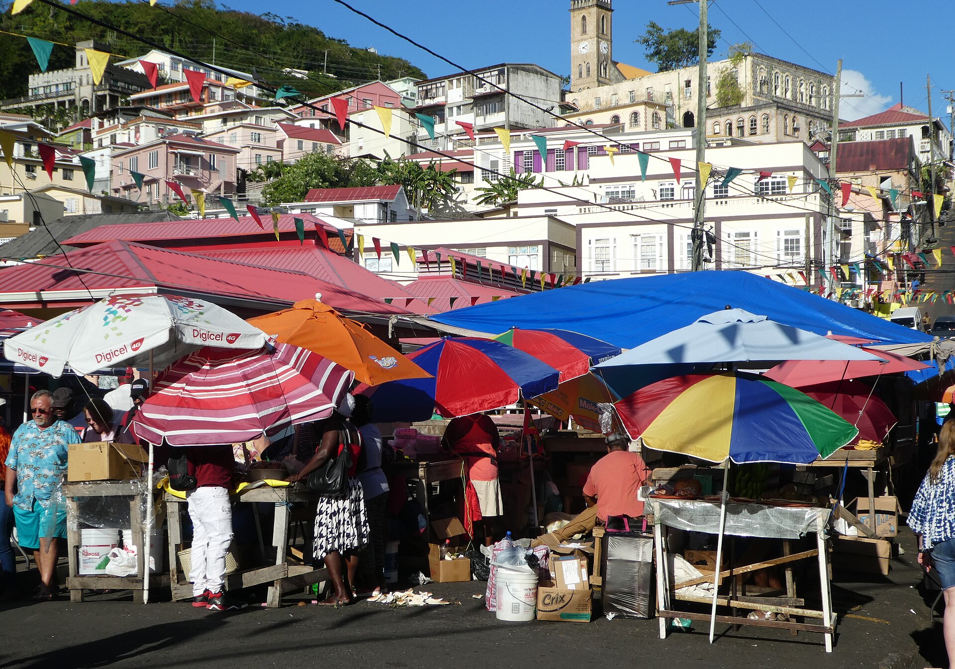 Vendors and shoppers under colored umbrellas at the open-air market in St George's, Grenada