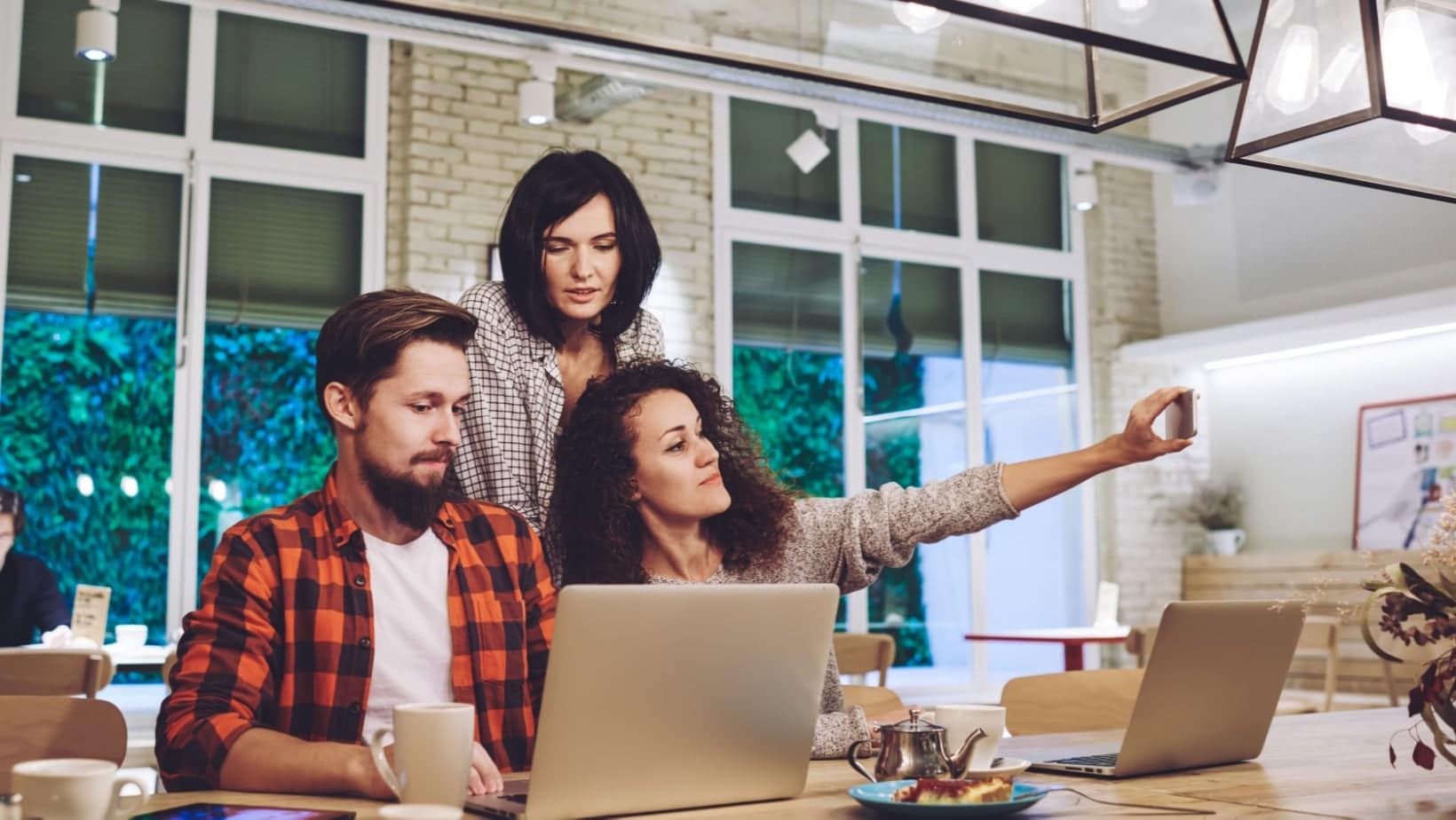 A group of people working and talking together around laptops at a shared table