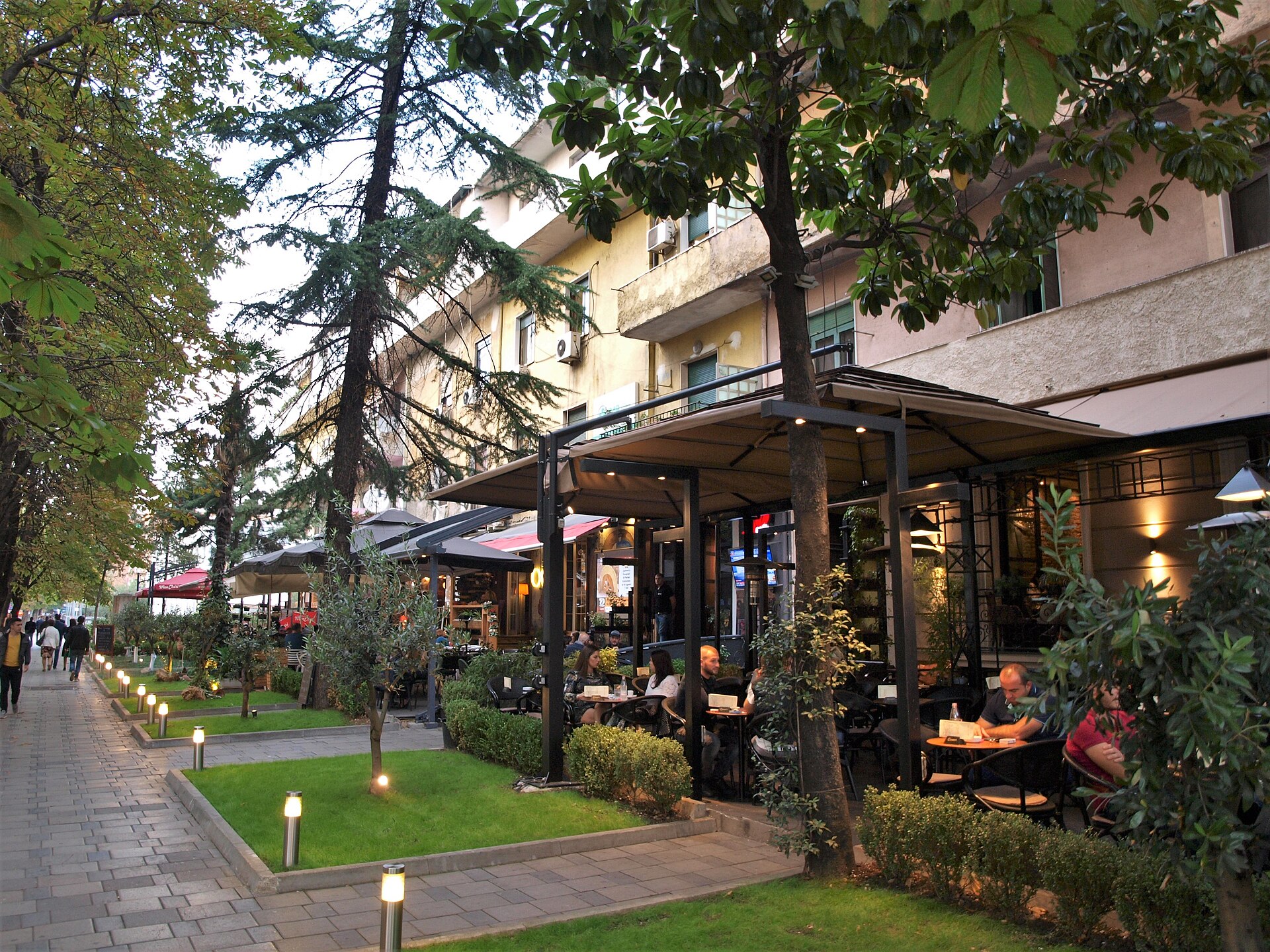Evening cafe terraces under the trees on a tree lined street in central Tirana