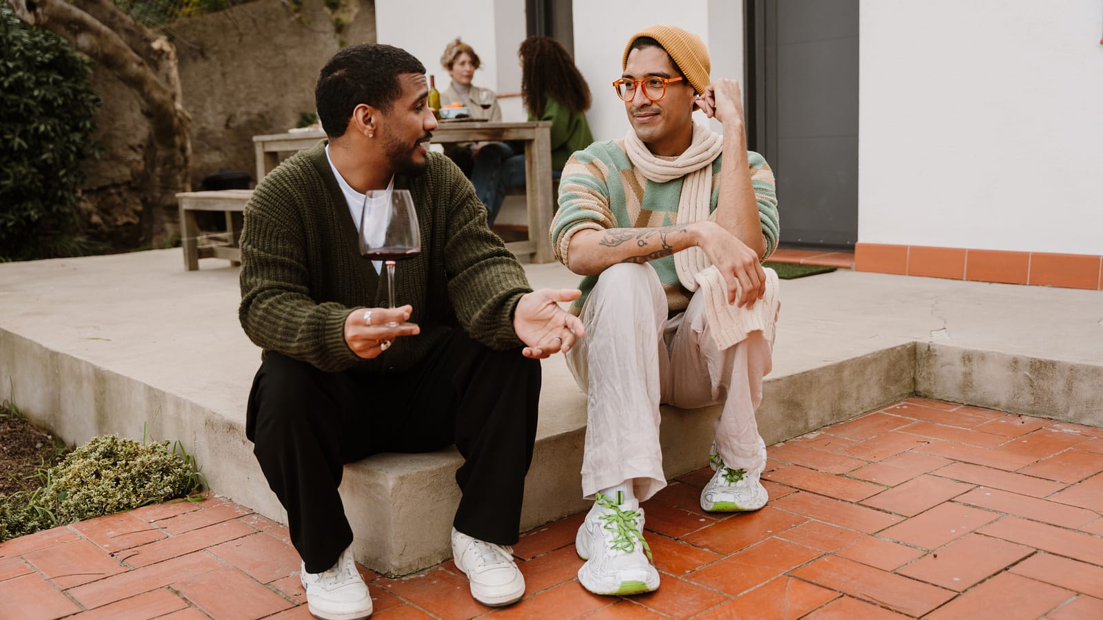 Two people talking over a glass of wine on a terrace